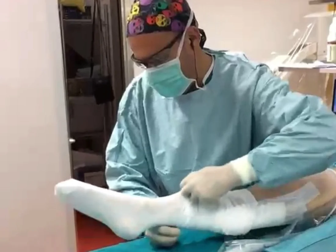 Il Dott. Russo applica il bendaggio alla gamba di un paziente in sala