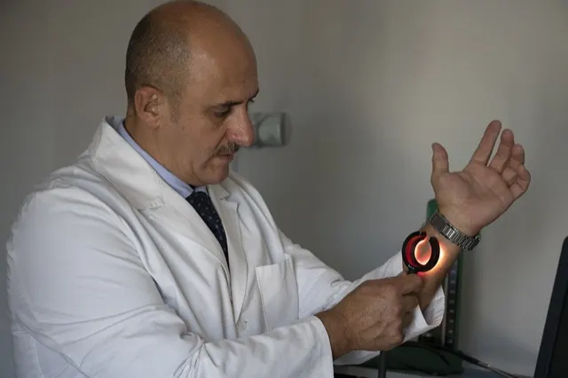 Il Dott. Russo mostra la luce rossa della fibra laser sul polso
