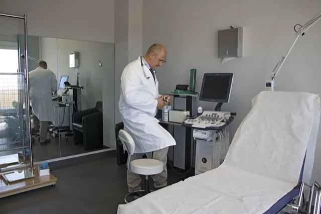 Il Dott. Russo prepara l'ecocolordoppler accanto al lettino visita